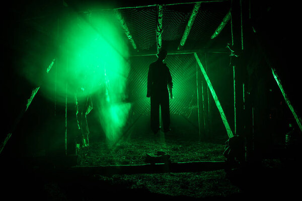 Horror view silhouette of hanged man on scaffold at night with fog and toned light on background. Execution (or suicide) decoration. Horror Halloween concept.