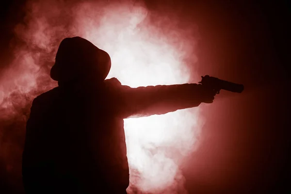 ダークで攻撃する準備ができてのピストルを持った男のシルエット トーン霧の背景や危険な山賊持株銃手 武器のテーマの装飾が施されたテロリストを撮影 — ストック写真
