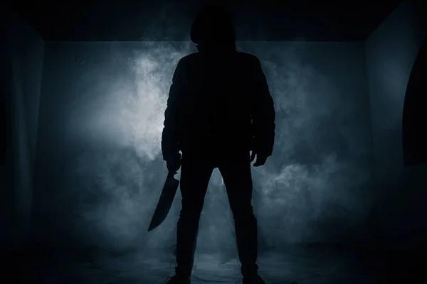 危険なフード男は暗闇の中で立っていると ナイフを保持します 顔を見ていないことができます 犯罪概念をコミット — ストック写真