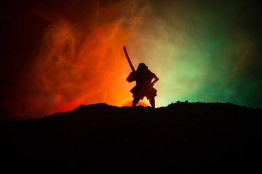 Savaşçı bir kılıç siluet bir gökyüzü ninja ile. Samuray koyu tonda sisli arka plan ile dağın zirvesinde. Seçici odak