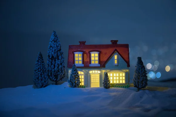 圣诞节和新年微型房子在雪中与冷杉树 小玩具房子在雪与树和 Bokeh 城市灯在背景 圣诞装饰品假期理念 — 图库照片
