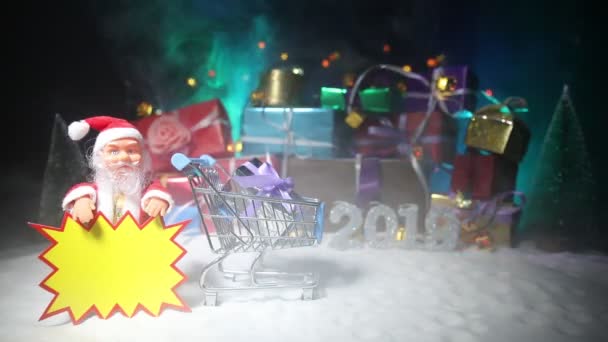 新年或圣诞假期购物的概念 商店促销活动 圣诞老人在雪地上提着手推车 背景上的礼品盒堆叠 文字贴纸上的空空间 — 图库视频影像