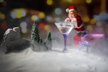 Winter Cocktail - Alcoholic drink and snow scene with a Christmas theme or Ideas and recipes for Christmas drink. Glass of martini on snow with Christmas decoration, copy space clipart