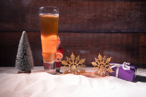 Mug of beer with Christmas decoration. Glass of light beer with foam in snow with creative New Year holiday artwork. Copy space