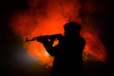 Saldırı tüfeği koyu tonda sisli arka plan veya tehlikeli bir haydut silah elinde tutan saldırmaya hazır olan adam silüeti. Terörist silah Tema dekor ile çekim