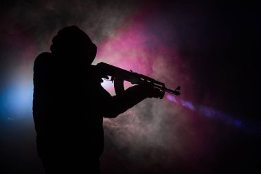 Saldırı tüfeği koyu tonda sisli arka plan veya tehlikeli bir haydut silah elinde tutan saldırmaya hazır olan adam silüeti. Terörist silah Tema dekor ile çekim