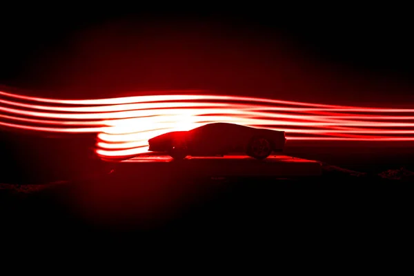 The car in the shadows with glowing lights in low light, or silhouette of sport car dark background. Selective focus