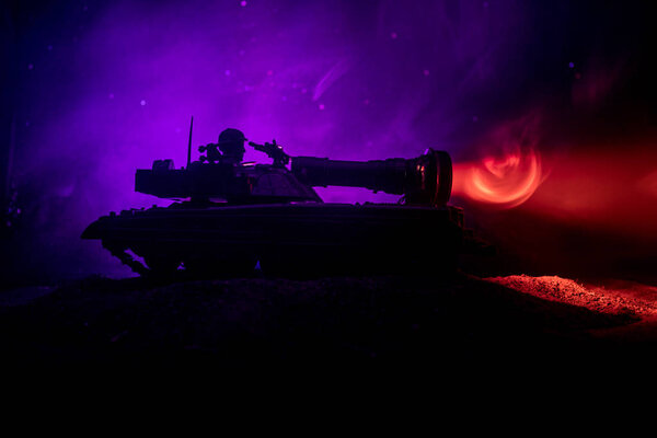 War Concept. Armored Tank Silhouette Below foggy fire sky at night. Attack scene. Toy decoration. Selective focus