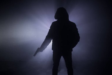 Tabanca dark saldırı için hazır olan adam silüeti sisli arka plan veya tehlikeli bir haydut holding silahı elinde tonda. Terörist silah Tema dekor ile çekim