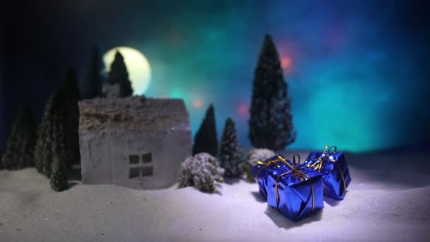 夜もみの木に雪の中でミニチュアの家のクリスマスと新年ツリーに雪の上の小さなおもちゃの家 お祭りの背景 クリスマスの装飾 ホリデイ コンセプト — ストック動画