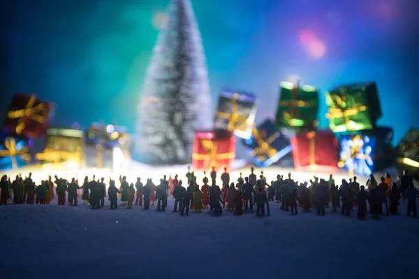 New year or Christmas holiday shopping concept. Store promotions. Silhouette of a large crowd of people watching at a big fir tree and gift boxes. People on snow ready to shopping. Selective focus