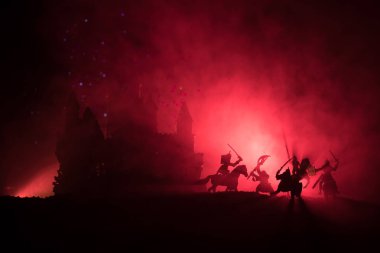 Süvari ve piyadelerle ortaçağ savaş sahnesi. Şekillerin siluetleri ayrı nesneler olarak, karanlık tonlu sisli arka planda ortaçağ şatosuyla savaşan savaşçılar arasında. Seçici odak