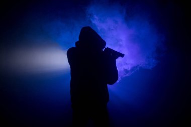 Tabanca dark saldırı için hazır olan adam silüeti sisli arka plan veya tehlikeli bir haydut holding silahı elinde tonda. Terörist silah Tema dekor ile çekim