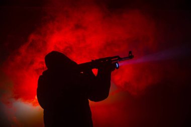 Saldırı tüfeği koyu tonda sisli arka plan veya tehlikeli bir haydut silah elinde tutan saldırmaya hazır olan adam silüeti. Terörist silah Tema dekor ile çekim
