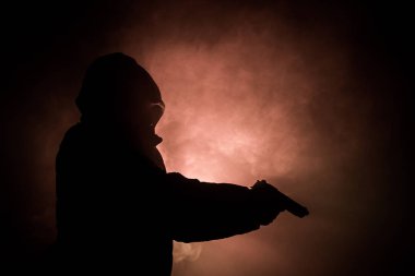 Tabanca dark saldırı için hazır olan adam silüeti sisli arka plan veya tehlikeli bir haydut holding silahı elinde tonda. Terörist silah Tema dekor ile çekim