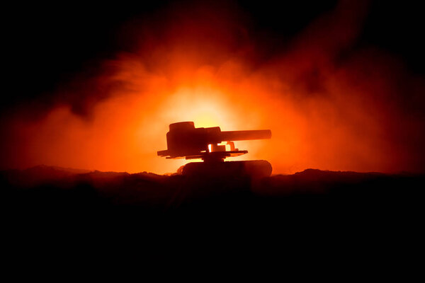 War Concept. Armored Tank Silhouette Below foggy fire sky at night. Attack scene. Toy decoration. Selective focus
