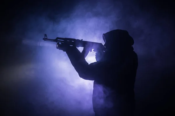 stock image Silhouette of man with assault rifle ready to attack on dark toned foggy background or dangerous bandit holding gun in hand. Shooting terrorist with weapon theme decor