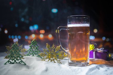 Kupa bira Noel dekorasyonu ile. Bardak köpüklü yaratıcı yeni yıl tatil sanat eseri ile karda hafif bira. Kopya alanı