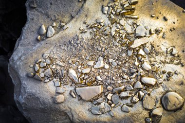 A pile of Gold nugget grains, on big river stone. Golden texture. Selective focus clipart