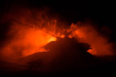 Savaş kavramı. Zırhlı Tank siluet aşağıda sisli yangın gökyüzü gece. Saldırı sahne. Oyuncak dekorasyon. Seçici odak