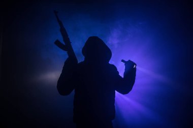 Saldırı tüfeği koyu tonda sisli arka plan veya tehlikeli bir haydut silah elinde tutan saldırmaya hazır olan adam silüeti. Terörist silah Tema dekor ile çekim
