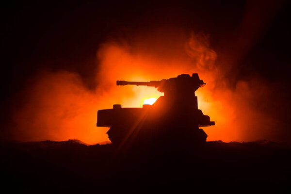 War Concept. Armored Tank Silhouette Below foggy fire sky at night. Attack scene. Toy decoration. Selective focus