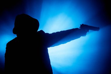 Tabanca dark saldırı için hazır olan adam silüeti sisli arka plan veya tehlikeli bir haydut holding silahı elinde tonda. Terörist silah Tema dekor ile çekim