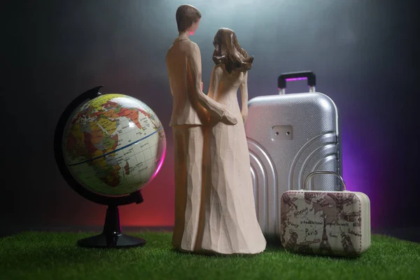 刚刚结婚的旅行概念 艺术品桌子装饰与夫妇附近的行李箱准备蜜月 深蓝色背景 选择性对焦 — 图库照片