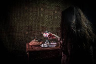 Kadın eli, düşük ışık siyah çay bardak salon halı ile iç. Doğu çay kavramı. Antika ahşap yüzey Doğu snacks. Seçici odak