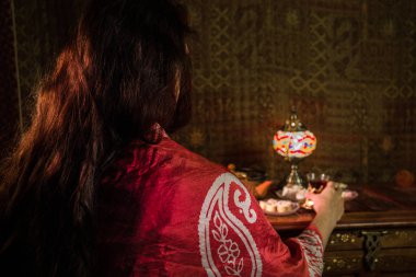 Kadın eli, düşük ışık siyah çay bardak salon halı ile iç. Doğu çay kavramı. Antika ahşap yüzey Doğu snacks. Seçici odak