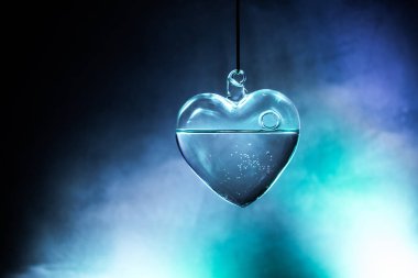 Valentines Day Concept. Glass transparent heart on dark, glass heart glows, glass painting, black background. Emptry space for your text clipart