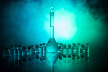 Eczane ve kimya teması. Araştırma laboratuarında çözeltisi olan cam deney şişesi. Bilim ve tıbbi geçmiş. Koyu renk arkaplan üzerinde laboratuvar test tüpleri, bilimsel araştırma ekipmanları konsepti