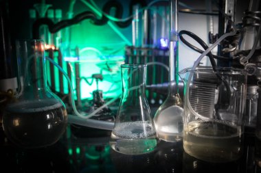 Eczane ve kimya teması. Araştırma laboratuarında çözeltisi olan cam deney şişesi. Bilim ve tıbbi geçmiş. Koyu renk arkaplan üzerinde laboratuvar test tüpleri, bilimsel araştırma ekipmanları konsepti