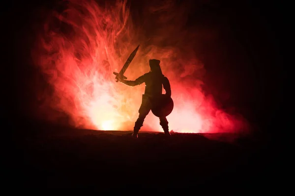 Medieval battle scene. Silhouette of warrior on dark toned foggy background. Night scene. Selective focus