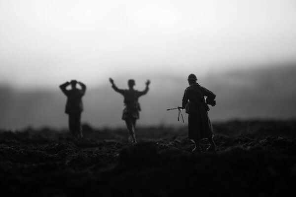 Battle scene. Military silhouettes fighting scene on war fog sky background. A German soldiers raised arms to surrender. Plastic toy soldiers with guns taking prisoner the enemy soldier. Artwork