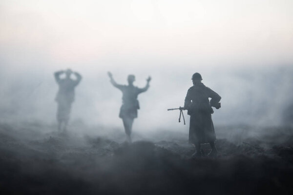 Battle scene. Military silhouettes fighting scene on war fog sky background. A German soldiers raised arms to surrender. Plastic toy soldiers with guns taking prisoner the enemy soldier. Artwork