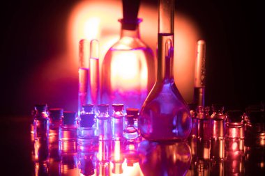 Eczane ve kimya teması. Araştırma laboratuarında çözeltisi olan cam deney şişesi. Bilim ve tıbbi geçmiş. Koyu renk arkaplan üzerinde laboratuvar test tüpleri, bilimsel araştırma ekipmanları konsepti