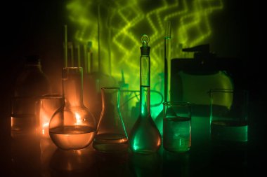 Eczane ve kimya teması. Araştırma laboratuarında çözeltisi olan cam deney şişesi. Bilim ve tıbbi geçmiş. Koyu renk arkaplan üzerinde laboratuvar test tüpleri, bilimsel araştırma ekipmanları konsepti