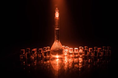 Eczane ve kimya teması. Araştırma laboratuarında çözeltisi olan cam deney şişesi. Bilim ve tıbbi geçmiş. Koyu renk arkaplan üzerinde laboratuvar test tüpleri, bilimsel araştırma ekipmanları konsepti