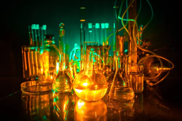 Pharmacy and chemistry theme. Test glass flask with solution in research laboratory. Science and medical background. Laboratory test tubes on dark toned background , science research equipment concept