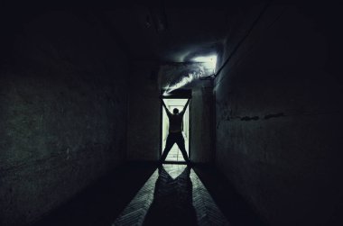 Ürpertici siluet koyu terk edilmiş binada. Korku manyak genel kavram ya da kabine kapılar ile karanlık koridor ve ışıkları ile Kapıda duran korkunç korku kişi silueti hakkında