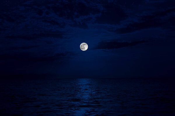 Full moon rising over sea at night with copy space. big full moon reflecting in a sea