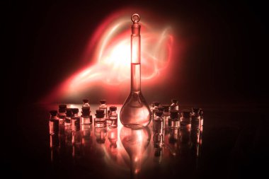 Eczane ve kimya teması. Araştırma laboratuarında çözeltisi olan cam deney şişesi. Bilim ve tıbbi geçmiş. Koyu renk arkaplan üzerinde laboratuvar test tüpleri, bilimsel araştırma ekipmanları konsepti