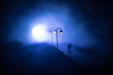 Resim dekorasyon. Siluet sokak ışıkların altında gece yürüyen bir çift. Sis içinde huzurlu bir atmosfer. Sisli hava. Aşk kavramı. Seçici odak
