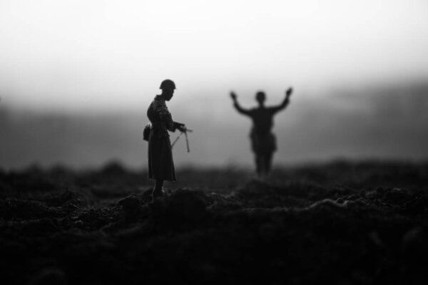 Battle scene. Military silhouettes fighting scene on war fog sky background. A German soldiers raised arms to surrender. Plastic toy soldiers with guns taking prisoner the enemy soldier. Artwork