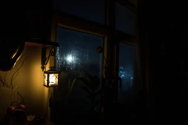 Night scene of Moon seen through the window from dark room. Night sky inside dark room viewing from window with old vintage lantern. Long exposure shot