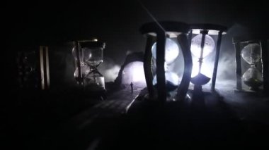 Zaman kavramı. Kum bir kum saati için bir son tarih saymak aşağı olarak geçen süre ölçümünü cam ampuller geçiyor. Hourglasses Silhouette koyu arka plan üzerinde duman. Çiçeklerle