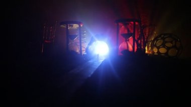 Zaman kavramı. Kum bir kum saati için bir son tarih saymak aşağı olarak geçen süre ölçümünü cam ampuller geçiyor. Hourglasses Silhouette koyu arka plan üzerinde duman. Çiçeklerle