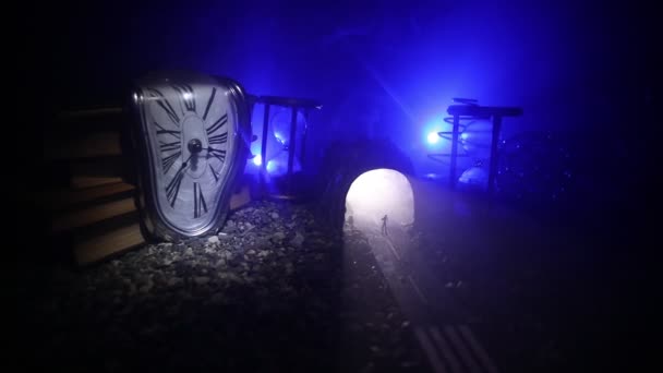 Concepto de tiempo. Arena que pasa a través de las bombillas de vidrio de un reloj de arena que mide el tiempo que pasa, ya que cuenta hasta un plazo. Silueta de clepsidras en humo sobre fondo oscuro. Con flores — Vídeo de stock