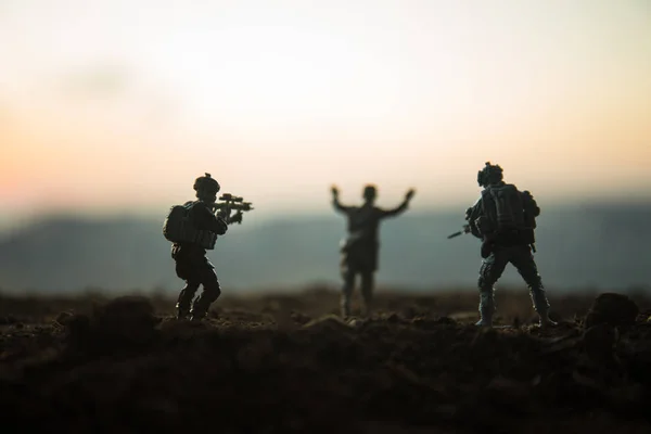 Battle scene. Military silhouettes fighting scene on war fog sky background. A German soldiers raised arms to surrender. Plastic toy soldiers with guns taking prisoner the enemy soldier. Artwork